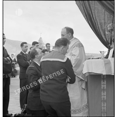 L'aumônier du cuirassé Dunkerque donne la communion à un capitaine de frégate lors d'une messe célébrée à bord du navire.