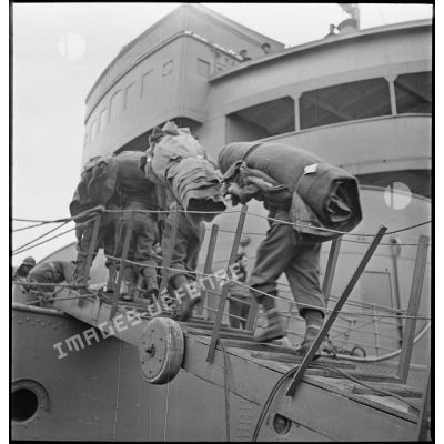 Des chasseurs alpins du 13e bataillon de chasseurs alpins (BCA) embarquent des couvertures par la coupée à bord du croiseur auxiliaire le Ville d'Oran à destination de l'Ecosse puis de la Norvège.