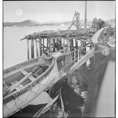 Récupération de matériels divers par des marins français dans le port de Namsos en ruine.