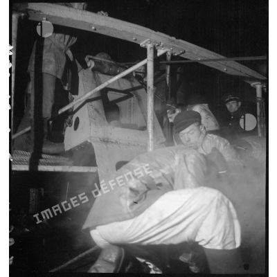 Deux marins travaillent sur un treuil lors d'une mission de dragage de nuit à bord d'un chalutier réquisitionné pour servir de dragueur de mines.