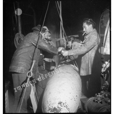 Au cours d'une mission de dragage de nuit, des marins fixent les filins sur un cochonnet de drague à bord d'un chalutier réquisitionné par la Marine nationale.