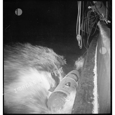Au cours d'une mission de dragage de nuit, des marins larguent le cochonnet de drague depuis un chalutier réquisitionné par la Marine nationale.