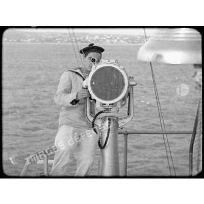 Un matelot met en oeuvre une lanterne Scott à bord d'un navire.