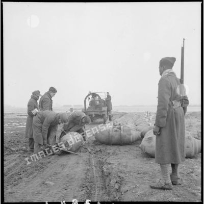 Transport de bombes par des prisonniers de guerre allemands sous l'oeil vigilant d'un tirailleur sénégalais.