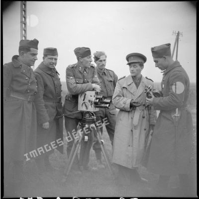 Un caméraman anglais s'appuie sur sa caméra, il est entouré de soldats.