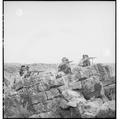 Des cavaliers druzes se tiennent postés derrière des rochers face à l'objectif.