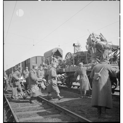 Des soldats perçoivent leur ration pour le repas le long d'une voie ferrée en gare de Trappes.