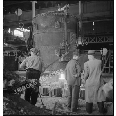 A l'intérieur de l'usine des ouvriers travaillent devant un fourneau.