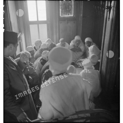 Photographie de groupe de pèlerins rassemblés dans une pièce d'une maison de Djeddah.