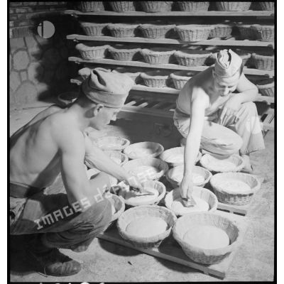 Des boulangers militaires préparent des pains avant la cuisson.