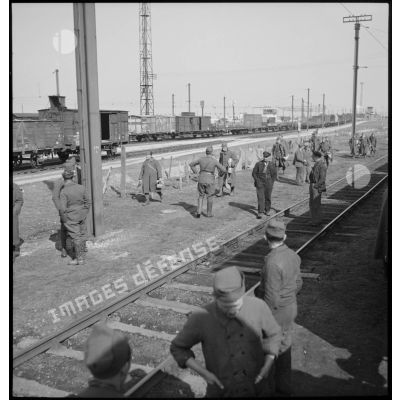 En gare de Trappes plan général d'une voie ferrée près de laquelle des soldats debout attendent.