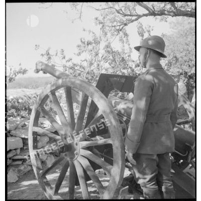 Un servant se tient près du canon de 75 mm modèle 1897.