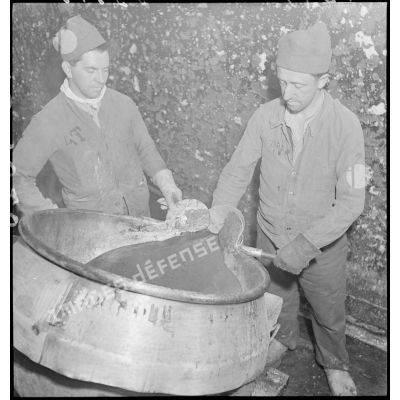 Deux ouvriers travaillent près d'un chaudron de mélinite.