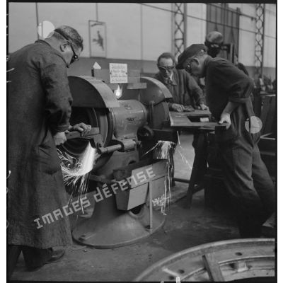 Des ouvriers passent à la meule des pièces métalliques dans l'atelier d'Issy-les-Moulineaux.
