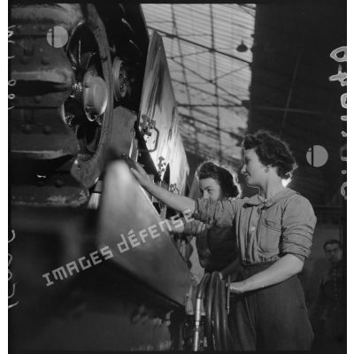 A l'atelier d'Issy-les-Moulineaux deux ouvrières travaillent sur le train de roulement d'un char Renault R40.