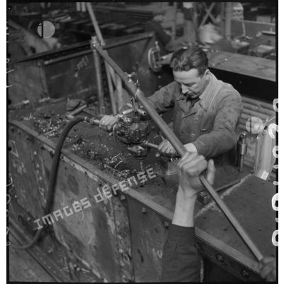 A l'atelier d'Issy-les-Moulineaux des ouvriers perforent la caisse d'un char B 1 bis avant de poser des rivets.