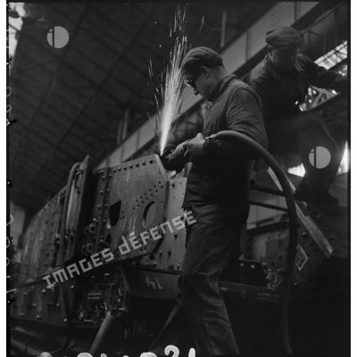A l'atelier d'Issy-les-Moulineaux un ouvrier ponce une plaque de blindage d'un char B 1 bis.
