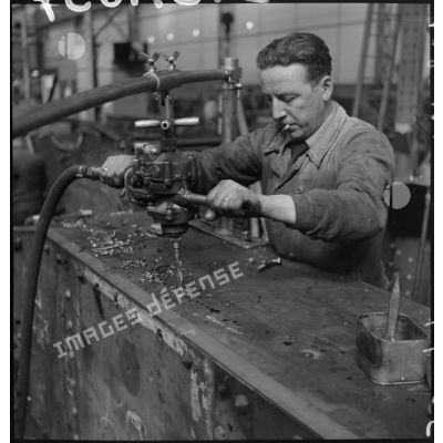 A l'atelier d'Issy-les-Moulineaux un ouvrier perfore la caisse d'un char B 1 bis avant de poser des rivets.