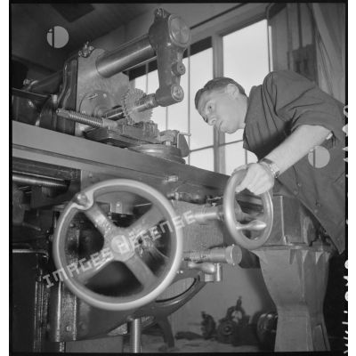 En atelier un apprenti de la cartoucherie de Vincennes travaille sur une machine-outil.