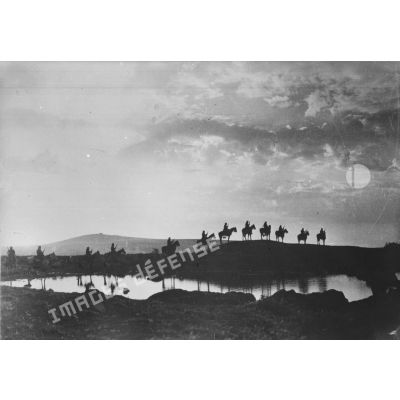 Auprès d'un point d'eau, un peloton de cavaliers druzes se détache en ombre chinoise.