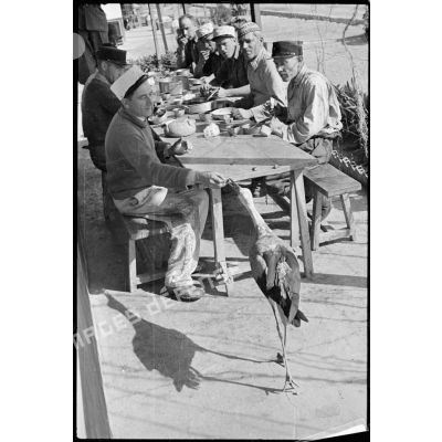 Des légionnaires du 1er REI mangent sur une table à l'extérieur.