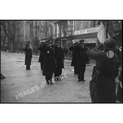Des amiraux saluent le drapeau d'une unité de l'armée de Terre lors de l'exécution de la Marseillaise au cours d'une prise d'armes.