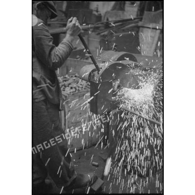 Ouvrier affûtant un outil sur une meule à l'arsenal de Brest.