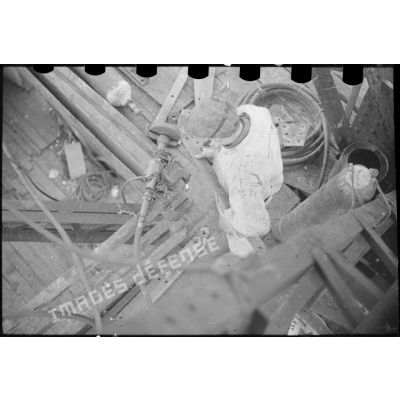 Un ouvrier polit une pièce de métal sur une meule à l'arsenal de Brest.
