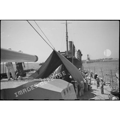 Une tente de camouflage est dressée sur la plage arrière du croiseur lourd Duquesne à quai.