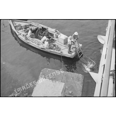 Sortie de l'eau d'un scaphandrier du croiseur lourd Duquesne, probablement à l'issue d'une mission d'inspection de la coque du navire.