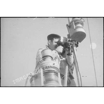 Caméraman du service cinématographique de la Marine filmant avec une caméra Bell et Howell à bord du contre-torpilleur Le Malin.