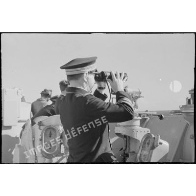 Le capitaine de vaisseau Yves Hamon, commandant le croiseur la Marseillaise, observe l'horizon aux jumelles.