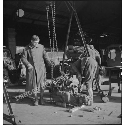 Deux prisonniers de guerre allemands reposent un moteur, dans les ateliers fixes des Issers.