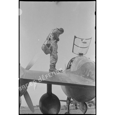 Le pilote ajuste son parachute avant de monter dans le cockpit de son avion.