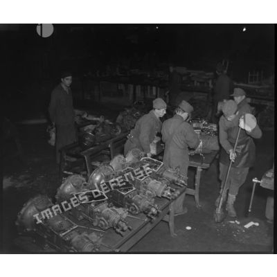 Des prisonniers de guerre allemands examinent avec soin des essieux et des transmissions, dans les ateliers fixes des Issers.
