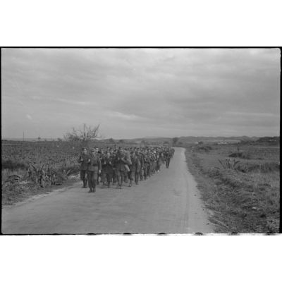 En Crète, dans le secteur de Maleme, une colonne de prisonniers italiens progresse sous la garde d'une sentinelle allemande.