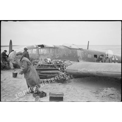 Des civils s'affairent autour d'un avion Heinkel  He-111 du KG-26, endommagé après un atterrissage forcé.