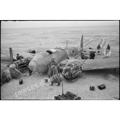 Des civils inspectent les nacelles moteur d'un avion de bombardement Heinkel He-111 du KG-26, endommagé après un atterrissage forcé sur la côte allemande. Ce bombardier Heinkel He 111H 2.KG26 de retour de Scapa-Flow a fait un atterrissage sur une plage à l'ouest de Cuxhaven (20 mars 1940) à  bord, un seul aviateur décède lors de l'atterrisage forcdé, il s'agit de Hans Baehr.