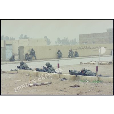 Un groupe de combat du 3e RIMa (régiment d'infanterie de marine) est en garde dans une rue d'Al Salman, des marsouins postés derrière un muret et le long d'un mur.