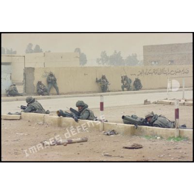 Un groupe de combat du 3e RIMa (régiment d'infanterie de marine) est en garde dans une rue d'Al Salman, des marsouins postés derrière un muret et le long d'un mur.