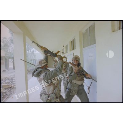 Des marsouins du 3e RIMa (régiment d'infanterie de marine) défoncent des portes de maisons d'Al Salman avec des fusils AK-47 pris aux militaires irakiens. Les marsouins portent leur équipement individuel, un S-3P (survêtement de protection à port permanent) NBC (risque nucléaire, bactériologique et chimique) et leur fusil d'assaut FAMAS. Certains ont en plus un émetteur-récepteur TRPP-11.
