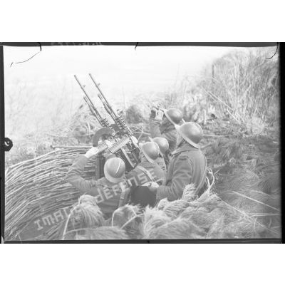 Des soldats servent des mitrailleuses Hotchkiss modèle 1914 jumelées sur affût double de marine.