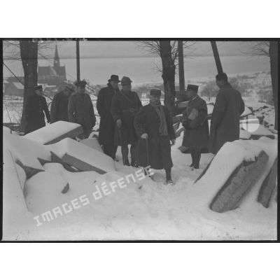 Photographie de groupe de l'ambassadeur du Canada en France, Monsieur Vanier, et du général d'armée Réquin accompagnés de divers officiers qui marchent dans la neige lors d'une visite.