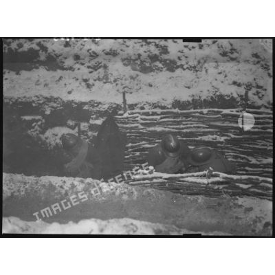 Sous la neige des soldats sont photographiés en plongée dans une tranchée.