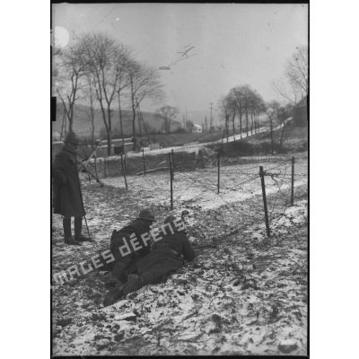 Couchés dans la neige deux soldats servent une mitrailleuse Hotchkiss M1914 de 8 mm.