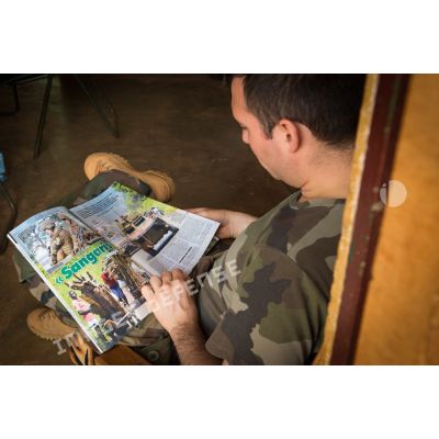 Au sein de la plateforme opérationnelle de défense de Bambari, un cadre du commandement du GTIA Turco entame la lecture d'un article du magazine Raid consacré à l'opération Sangaris.