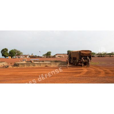 Au sein de la plateforme opérationnelle de défense de Bambari, trois soldats d'une compagnie logistique s'apprêtent à remplir une citerne souple grâce un camion-citerne Scania CCP 10.