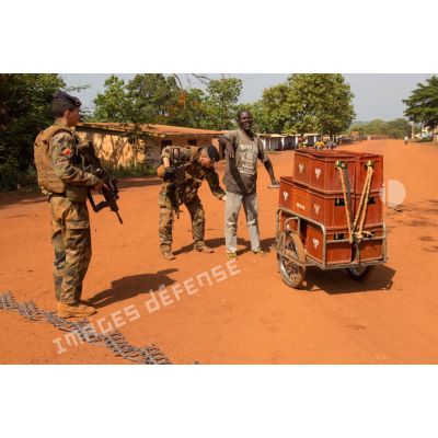 Tirailleurs de la compagnie Rouge du 1er RT du GTIA (groupement tactique interarmes) Turco contrôlant un civil, lors d'une mission de contrôle sur un check-point établi sur l'axe du marché central de Bambari, en compagnie des casques bleus de la MINUSCA (mission multidimensionnelle intégrée des Nations Unies pour la stabilisation en Centrafrique).