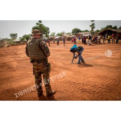 Sous les yeux d'un soldat du Génie de l'Air, des habitants du village de Makangé dressent les poteaux et les lignes d'un terrain de football récemment réalisé par le 25e RGA.