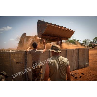 Des soldats du détachement du 3e RG du GTIA (groupement tactique interarmes) Turco remplissent de terre des Hesco bastions destinés à ériger un mur de fortification à l'aide d'une tractopelle EGRAP (engin du génie rapide de protection), lors de travaux de réaménagement de la POD (plateforme opérationnelle défense) de Bambari.